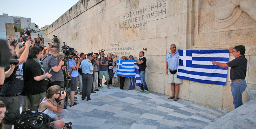 Anti-austerity protesters hold Greek flags as they shout slogans during a rally against the government’s agreement with its  creditors in front of the Tomb of the Unknown Soldier in Athens on Monday  (AP photo)