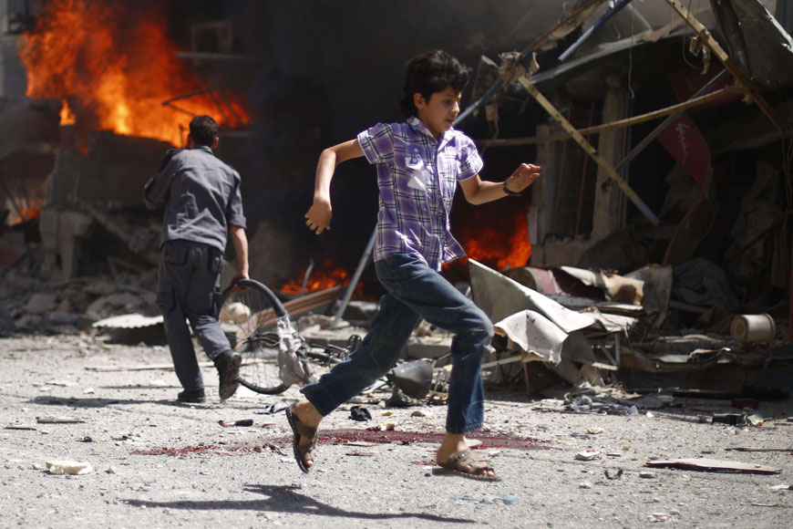 A Syrian youth runs past bloodstains and debris following air strikes by government forces on the rebel-held town of Douma on Thursday (AFP photo)