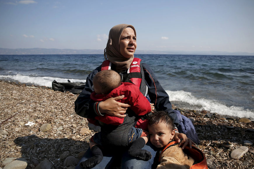A Syrian woman cries while holding her children moments after arriving on a dinghy on the island of Lesbos, Greece, on Sunday.  Greece, mired in its worst economic crisis in generations, has been found largely unprepared for a mass influx of refugees, mainly Syrians. Arrivals have exceeded 160,000 this year, three times as high as in 2014 (Reuters photo)