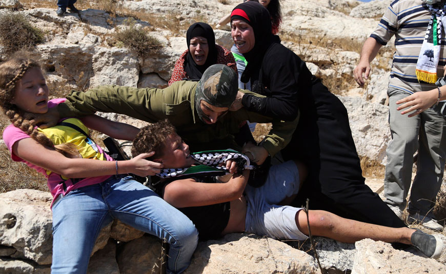 In this Friday photo, Palestinian women and youths scuffle with an Israeli soldier trying to arrest a 12-year-old boy during a protest near the West Bank village of Nebi Saleh. A video showing the incident has been viewed more than 2 million times on Facebook, and shined a light on Israeli military policies in the territory (AP photo)
