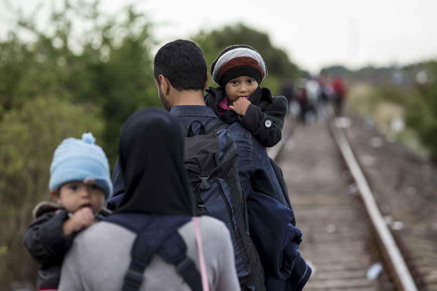 A migrant family from Syria walks along rail tracks as they arrive at a collection point in the village of Roszke in Hungary after crossing the border from Serbia on Sunday (Reuters photo)