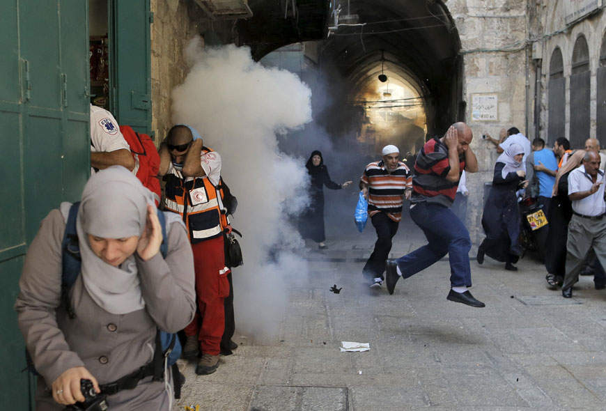 Palestinian protesters run away as Israeli forces throw a stun grenade in Jerusalem’s Old City on Monday (Reuters photo by Ammar Awad)