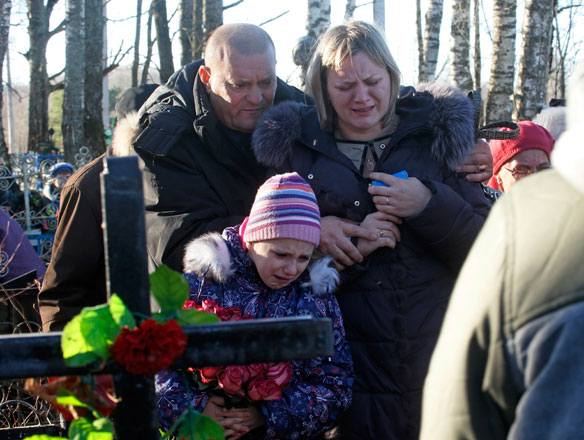 Pavel (left), the nephew of one of the plane crash victims Nina Lushchenko, reacts at her grave side with her daughter Veronika (right) and granddaughter, during her funeral at a cemetery in the village of Sitnya, Russia, Thursday (AP photo)
