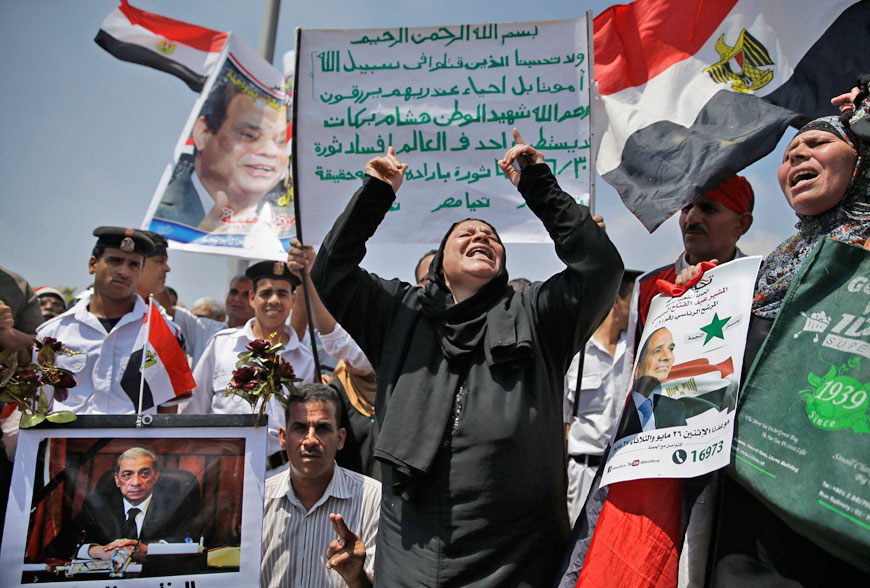 An Egyptian woman chants pro-government slogans on Tuesday, during the funeral of Egyptian Prosecutor General Hisham Barakat, killed in a bomb attack a day earlier, outside the Hussein Tantawi Mosque in Cairo, Egypt. Heavy security forces deployed across the Egyptian capital for the burial of Barakat, the top judicial official in charge of overseeing prosecution of thousands of Islamists. The poster at bottom left shows a photo of Barakat (AP photo)