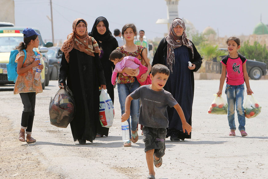 Civilians, who fled the violence in Hasaka city, carry their belongings as they arrive in Amouda town, east of Qamishli in Hasaka governorate, Syria, on Saturday (Reuters photo)