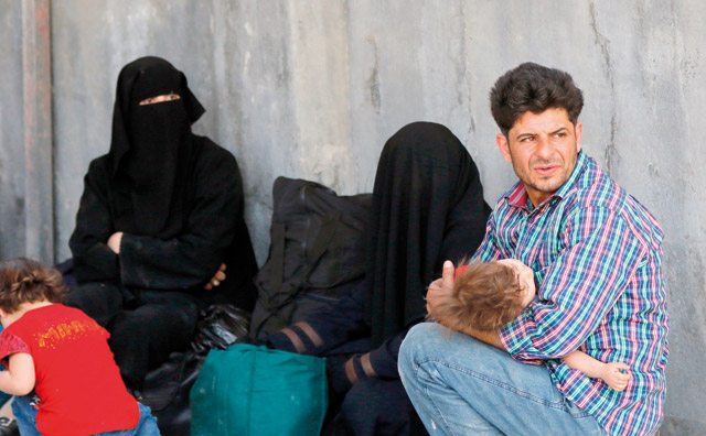 Residents of Al Qaboun, a formerly rebel-held northeastern suburb of Damascus, wait in an area designated by the Syrian government for their cases to be processed after the suburb was retaken by regime forces, on Tuesday during a tour guided by the government forces (AFP photo)