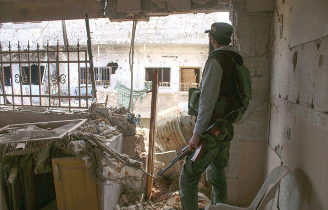 An opposition fighter looks out from a destroyed building in a rebel-held area in the southern Syrian city of Daraa on Sunday (AFP photo)