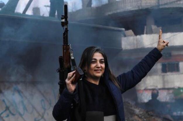   An armed woman flashes the V for victory sign as Syrian Kurds celebrate the fall of capital Damascus to anti-government fighters, in the city of Qamishli on December 8, 2024 (AFP photo)