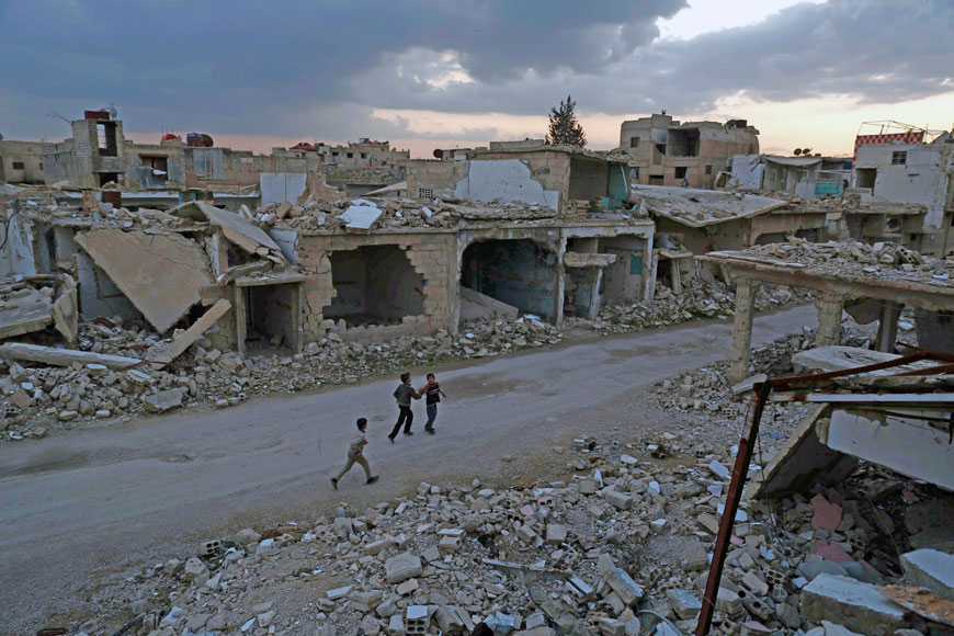 Syrian children walk past heavily damaged buildings in the rebel-held town of Douma, on the eastern edges of the capital Damascus, on Saturday on the first day of the landmark ceasefire agreement  (AFP photo)