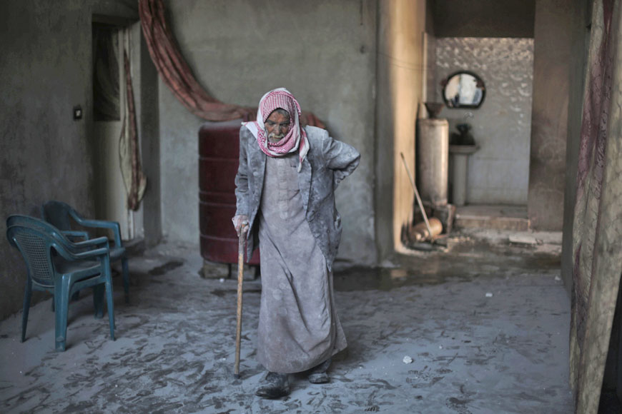 Syrian Abu Mohammed, covered with dust from explosions, walks in his home following reported air strikes by regime forces on the town of Al Nashabiyah in the Eastern Ghouta region, a rebel stronghold east of the capital Damascus, on Monday (AFP photo)