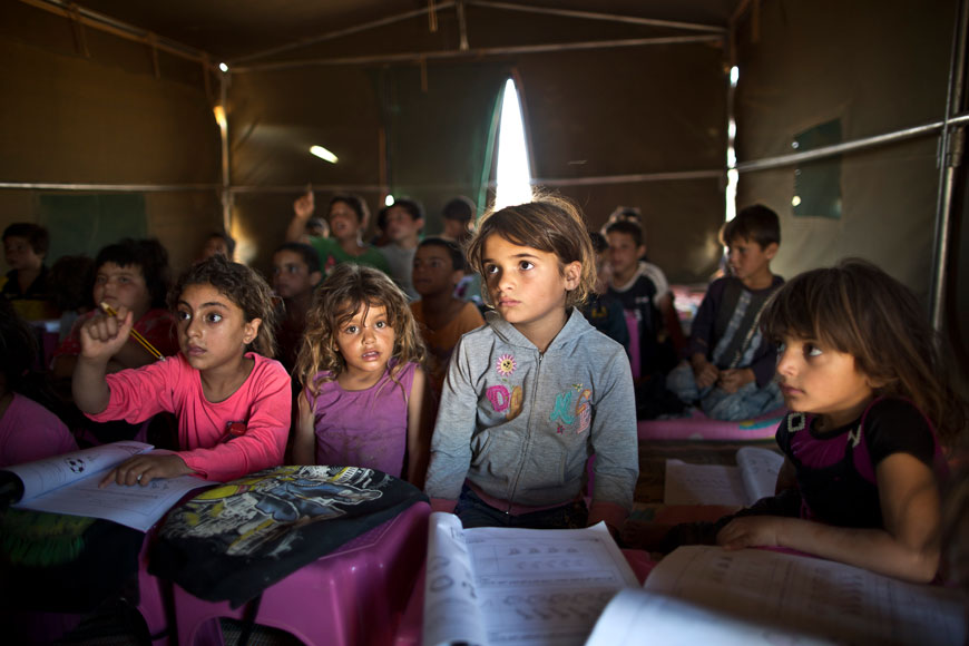 In this August 11, file photo, Syrian refugee children attend a class at a makeshift school set up in a tent at an informal tented settlement near the Syrian border on the outskirts of Mafraq, Jordan (AP photo by Muhammed Muheisen, File)