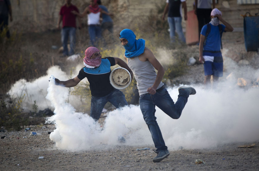 A Palestinian protester throws back a tear gas canister that was fired by Israeli troops during confrontations near Ramallah, West Bank, Thursday (AP photo by Majdi Mohammed)