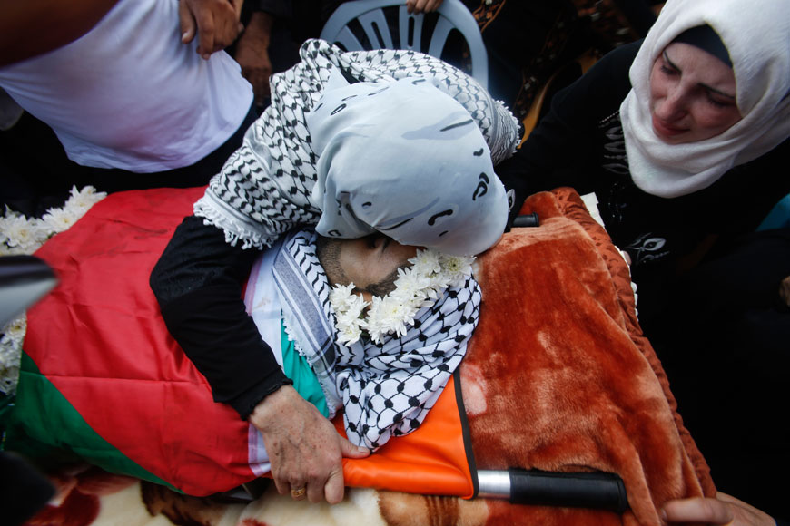 A relative hugs the body of Iyad Awawdeh, 26, during his funeral in the West Bank village of Dora, near Hebron, Saturday (AP photo by Nasser Shiyoukhi)