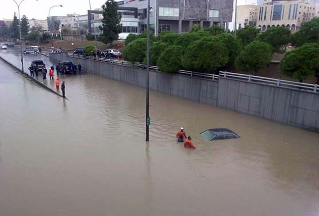 Local authorities try to salvage a vehicle submerged in the deluge in Amman on Thursday (Al Rai photo)