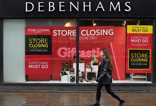 A pedestrian walks past ‘Store Closing’ signs in the window display of a Debenhams store in Manchester, northern England, on December 2, 2020 (AFP photo)
