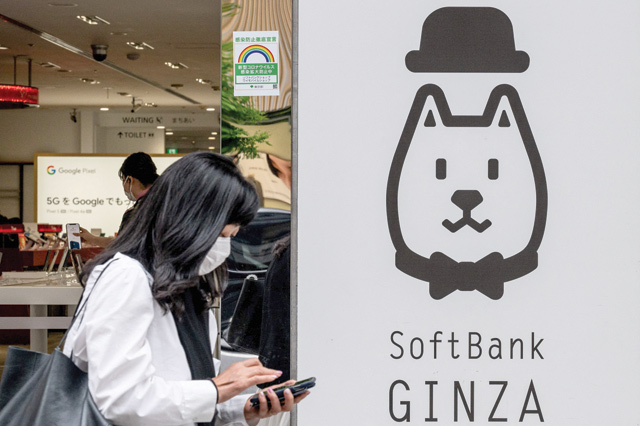 A woman walks past a logo of the SoftBank Group in Tokyo, on Wednesday (AFP photo)