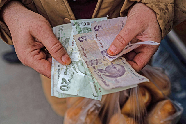 This photo taken on Saturday shows a resident counting Turkish lira banknote in Sultangazi district of Istanbul, after she bought bread at the Istanbul Municipality's cheap bread shop (AFP photo)