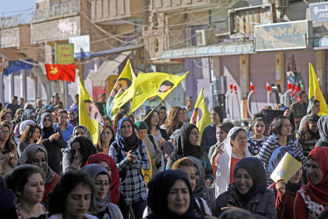 Syrian Kurds wave flags printed with the portrait of Kurdistan Workers Party leader Abdullah Ocalan as they demonstrate in Qamishli against Turkish shelling of Kurdish militia posts in northern Syria on Wednesday (AFP photo)