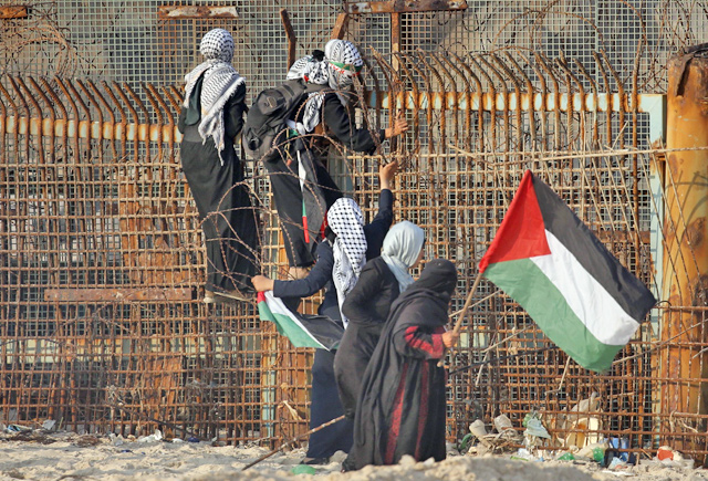 Palestinian protesters climb a fence during a demonstration on the beach near the maritime border with Israel, in the northern Gaza Strip, on Monday (AFP photo)