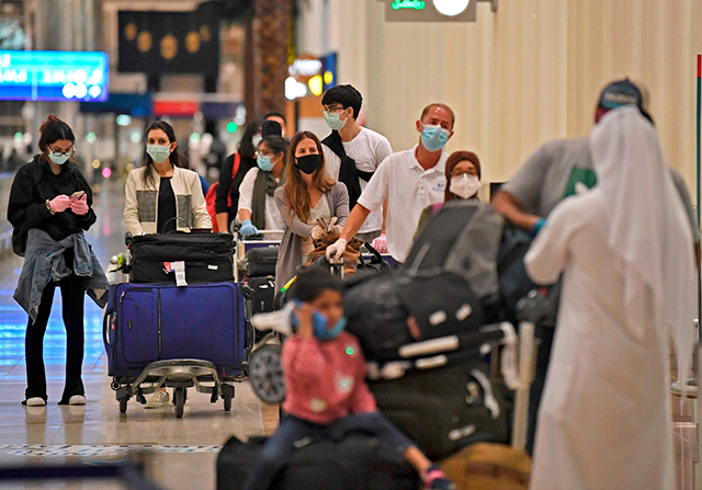 Passengers from an Emirates Airlines flight from London line up before being checked by health workers at Dubai International Airport on May 8 (AFP photo)