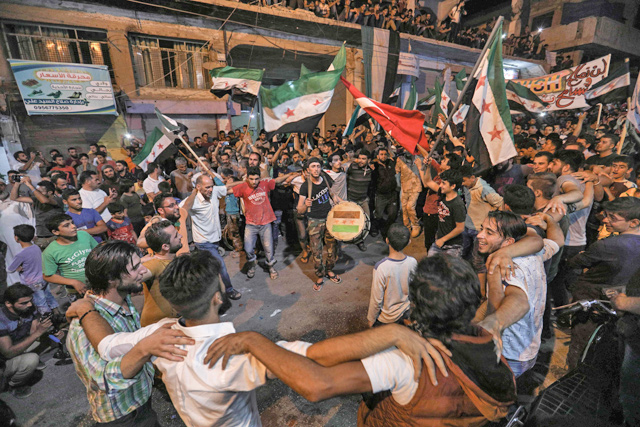 Syrians dance, chant slogans and strike drums while others wave flags of Turkey and the opposition, as they protest against the Syrian government during a demonstration in Binnish in the rebel-held northern Idlib province late on Monday (AFP photo)