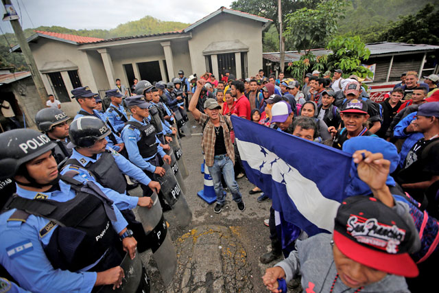 Honduran immigrants stand in front of Honduran police officers blocking the access to the Agua Caliente border with Guatemala as they try to join a migrant caravan heading to the US, in the municipality of Ocotepeque, Honduras, on Thursday (Reuters photo)