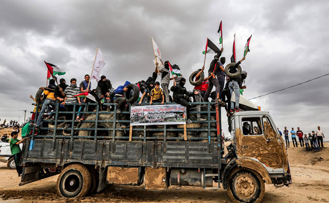 Palestinian protesters ride in a truck waving Palestinian flags as they bring tyres to be burnt for cover during confrontations along the border with Israel east of Gaza City on Friday (AFP photo)