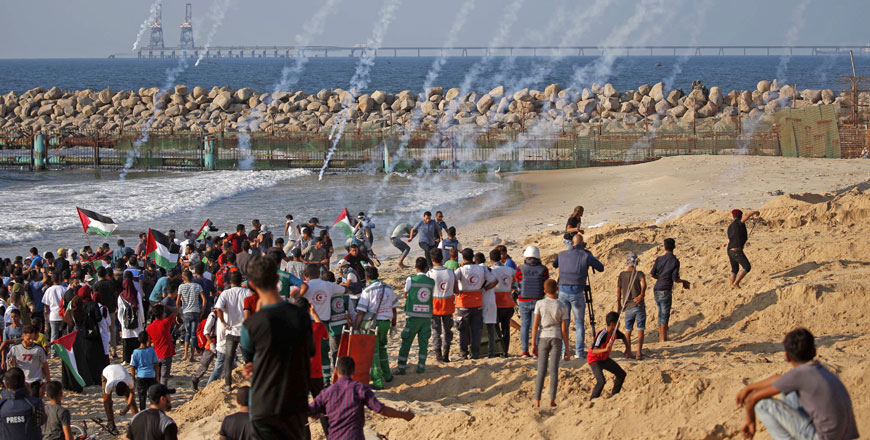 Trails of smoke from tear gas canisters fired by Israeli forces are seen as Palestinians protest on the beach near the maritime border with Israel, in the northern Gaza Strip, calling for the lift of the Israeli blockade on the coastal Palestinian enclave, on Monday (AFP Photo)