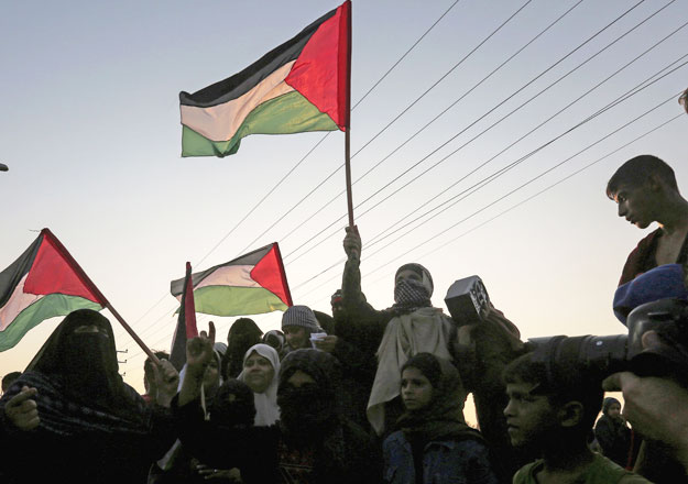 Palestinian protesters wave their national flags at sunset during a demonstration near the Erez crossing with Israel on Tuesday (AFP photo)