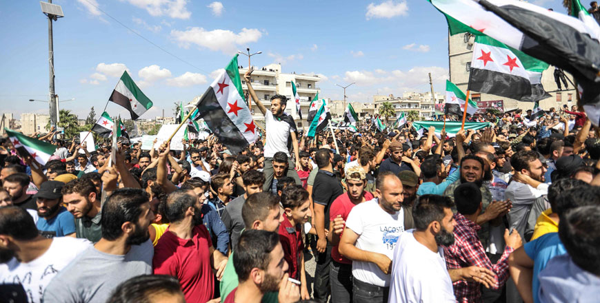 Syrians from the rebel-held northern city of Idlib and its surrounding towns wave the flag of the opposition and chant slogans as they gather for an anti-government demonstration in a main square in Idlib on Friday (AFP photo)