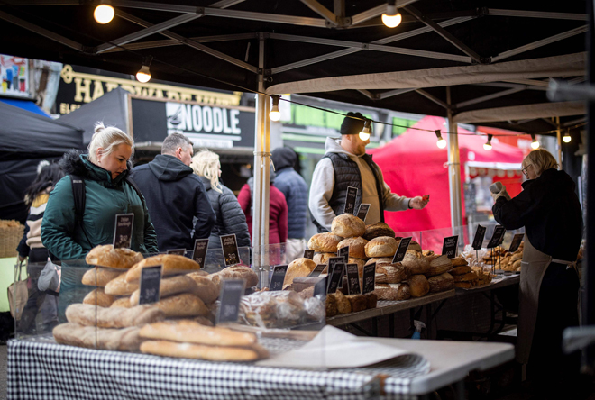 Customers shop for bread on a market stall in Walthamstow, east London on Sunday, amid increasing inflation (AFP photo)