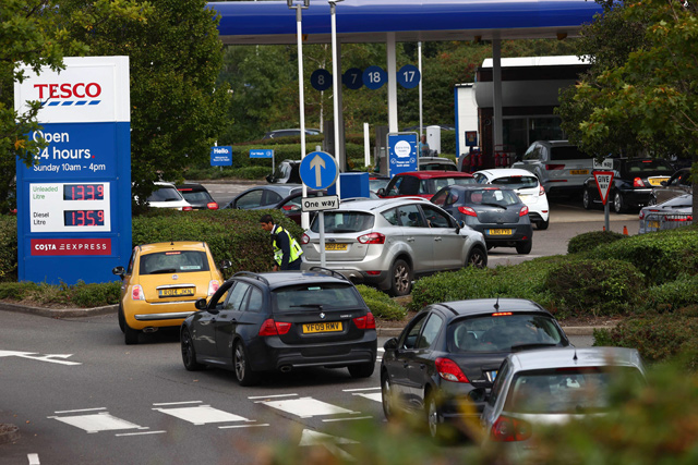 A security guard assists drivers queuing to fill up at a Tesco petrol station in Camberley, west of London, on Sunday (AFP photo)