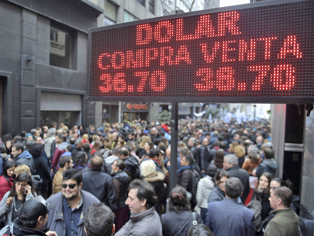 Demonstrators protesting against the economic policies of the government walk past in front of a bureau de exchange in Buenos Aires on Monday (AFP photo)