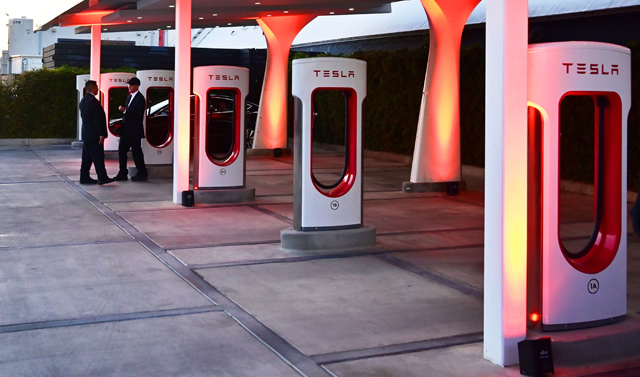 In this file photo taken on March 14, 2019, people stand beside charging stations before entry to see the unveiling of the new Tesla Model Y at the Tesla Design Center in Hawthorne, California (AFP photo)