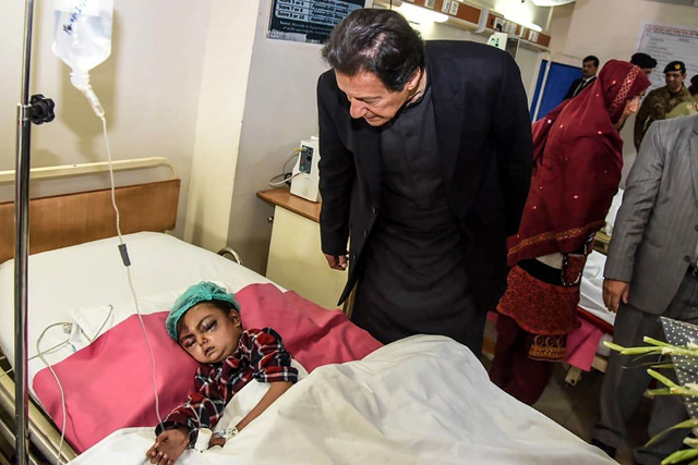 Pakistan’s Prime Minister Imran Khan (centre) looks at a young injured avalanche victim, on Wednesday, at a military hospital in Muzaffarabad, the capital of Pakistan-administered Kashmir   (AFP photo)