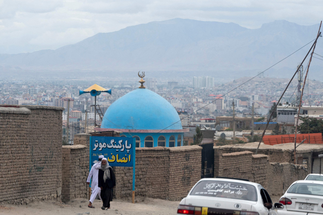Afghan men walk past the blue dome of a mosque a day after the blast in the outskirts of Kabul on Thursday (AFP photo)