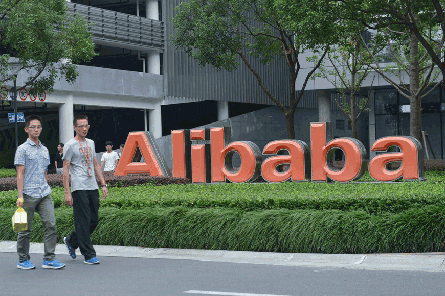 This file photo taken on May 27, 2022, shows staff members walking past the logo of Chinese e-commerce giant Alibaba at its headquarters in Hangzhou, in China's eastern Zhejiang province (AFP photo)