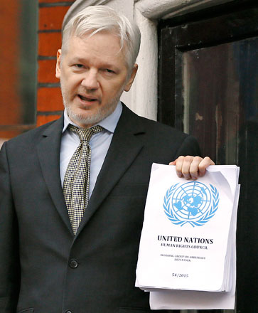 WikiLeaks founder Julian Assange, holding the UN report, speaks on the balcony of the Ecuadorean embassy in London, Friday (AP photo)