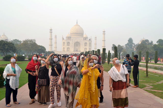 Foreign tourists wearing face masks visit the Taj Mahal under heavy smog conditions, in Agra, on Monday (AFP photo)