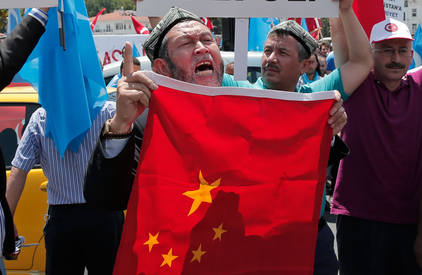 Uighurs living in Turkey and Turkish supporters chant slogans as they hold a Chinese flag before burning it during a protest near China's consulate in Istanbul on Sunday (AP photo)
