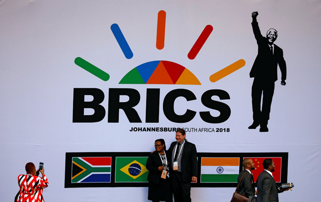 Delegates take pictures beneath a billboard outside the BRICS summit meeting in Johannesburg, South Africa, on Wednesday  (Reuters photo)