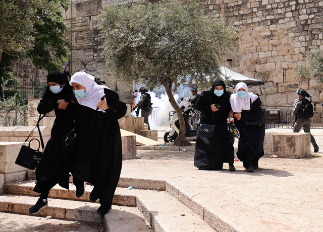   Palestinians run for cover from tear gas fired by Israeli forces in Jerusalem’s Old City on Monday (AFP photo)
