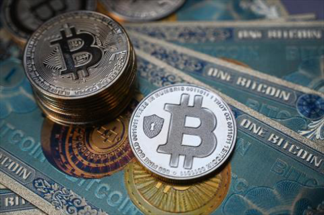 This illustration photo taken on July 19, 2021 in Istanbul shows a physical banknote and coin imitations of the Bitcoin crypto currency (AFP photo)