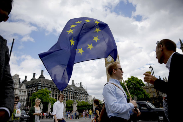A remain supporter on Friday stops to talk to people as he walks around with his European flag across the street from the Houses of Parliament in London (AP photo)
