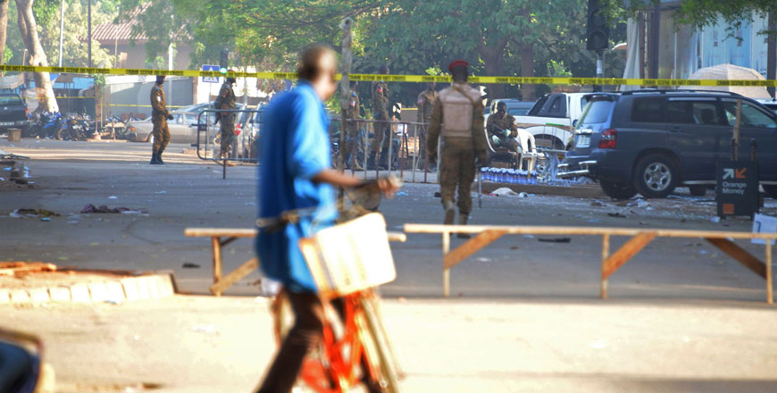 A cyclist watches military personnel outside the headquarters of the country’s defence forces in Ouagadougou on Saturday a day after dozens of people were killed in twin attacks on the French embassy and the country’s military (AFP photo)