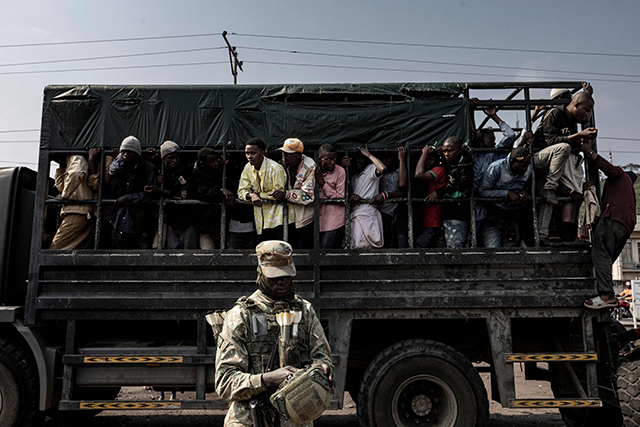 A member of the M23 movement stands guard as people board a truck during an enrolment of civilians, police officers, and former members of the Armed Forces of the Democratic Republic of Congo who allegedly decided to join the M23 movement voluntarily in Goma yesterday (AFP photo)