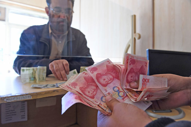 A Pakistani currency dealer counts Chinese currency for his customer at his shop in Quetta on Wednesday (AFP photo)