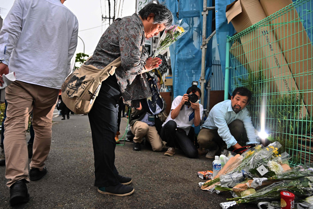A woman pays her respects next to flower tributes at the crime scene where a man stabbed 19 people, including children, in Kawasaki, on Tuesday (AFP photo)