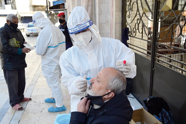 A healthcare worker collects a sample from a man during a coronavirus test in downtown Amman after Friday prayer (Photo by Amjad Ghsoun)