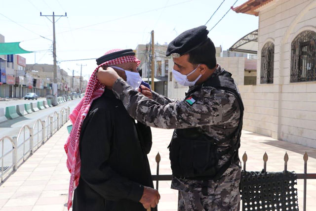 A police officer helps an elderly man put on a mask in this undated photo. On Monday, the Ministry of Health renewed its call on citizens to use the ‘Aman’ (Safety) application, which alerts users if they come into contact with a person infected with the virus (Petra file photo)